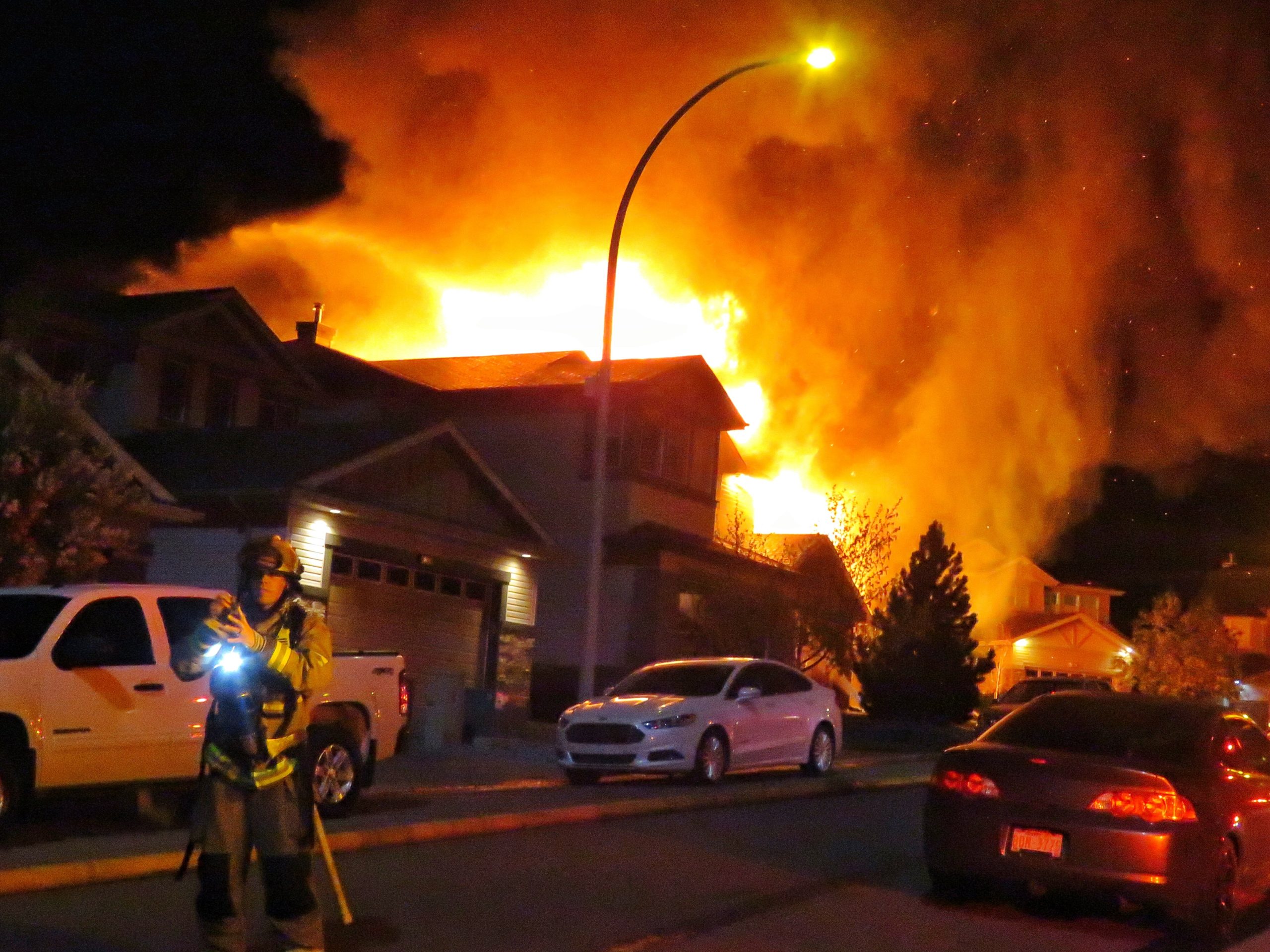 a fire engulfing multiple homes and cars as a firefighter walks away from the scene