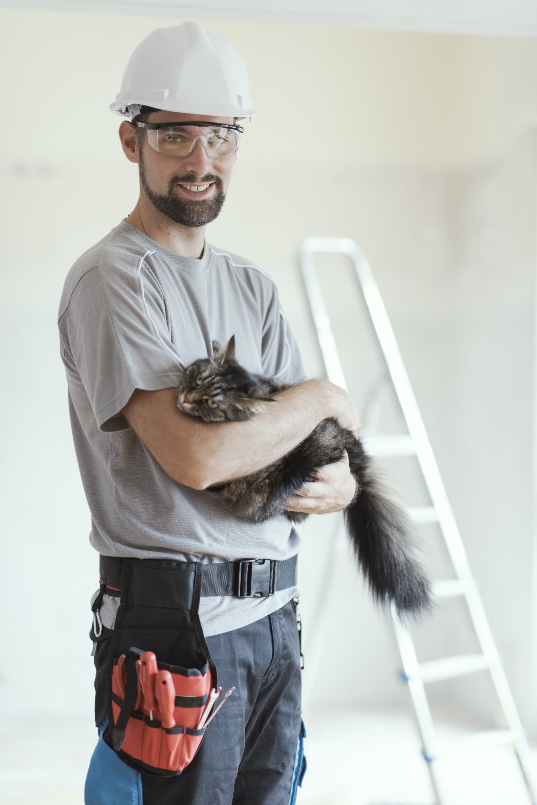 Man holding a cat and dressed in construction attire